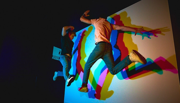 Visitors jumping in front of colorful shadow display at Paradox Museum.