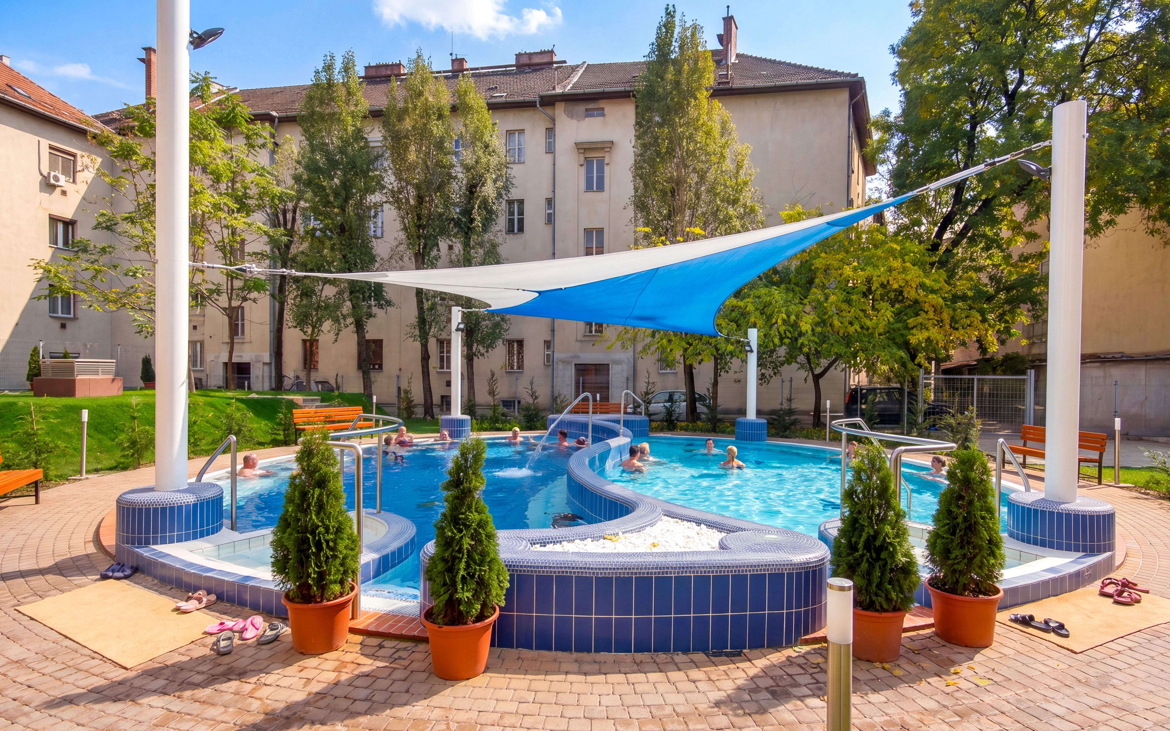 Outdoor pool area at Dandar Spa with people relaxing under a sunshade.