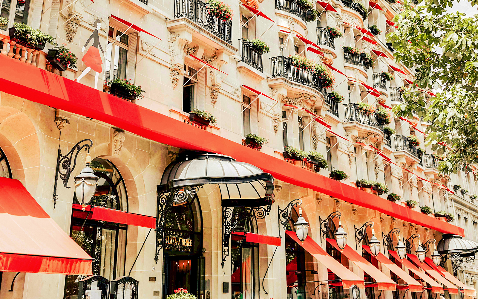 Facade of a luxury hotel with red awnings on Avenue Montaigne, Paris.