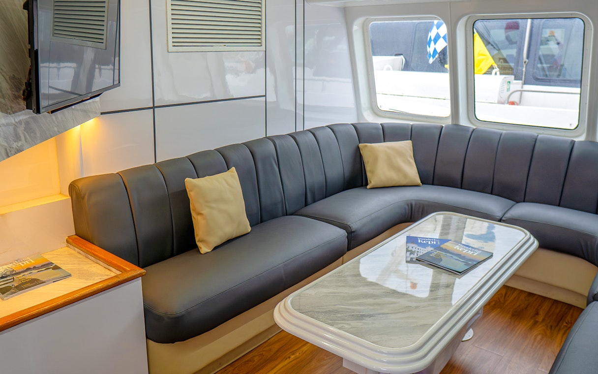 Ferry interior with cushioned seating and table, Singapore to Batam route.