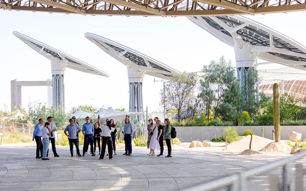 Guide leading a group tour at Expo City Dubai with futuristic structures in the background.