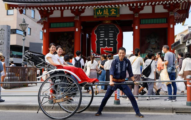 Rickshaw ride in Asakusa, Tokyo, with Senso-ji Temple gate in the background.