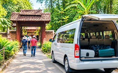 Private van parked near travelers entering a traditional gate in Chiang Mai.