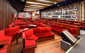 Reduta Jazz Club interior with red seating and musician portraits on walls.
