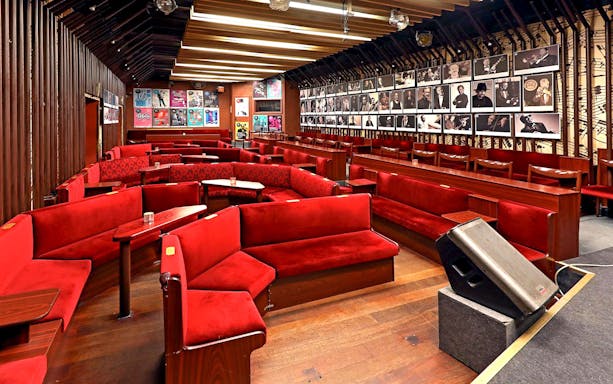 Reduta Jazz Club interior with red seating and musician portraits on walls.