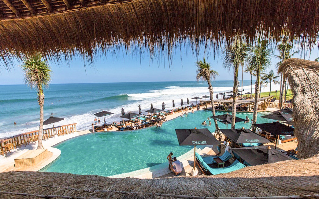 Finns Beach Club Bali poolside with ocean view and sun loungers.