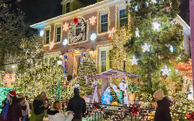 New York house adorned with Christmas lights and nativity scene during holiday bus tour.