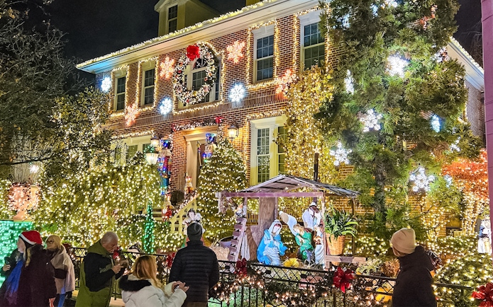 New York house adorned with Christmas lights and nativity scene during holiday bus tour.