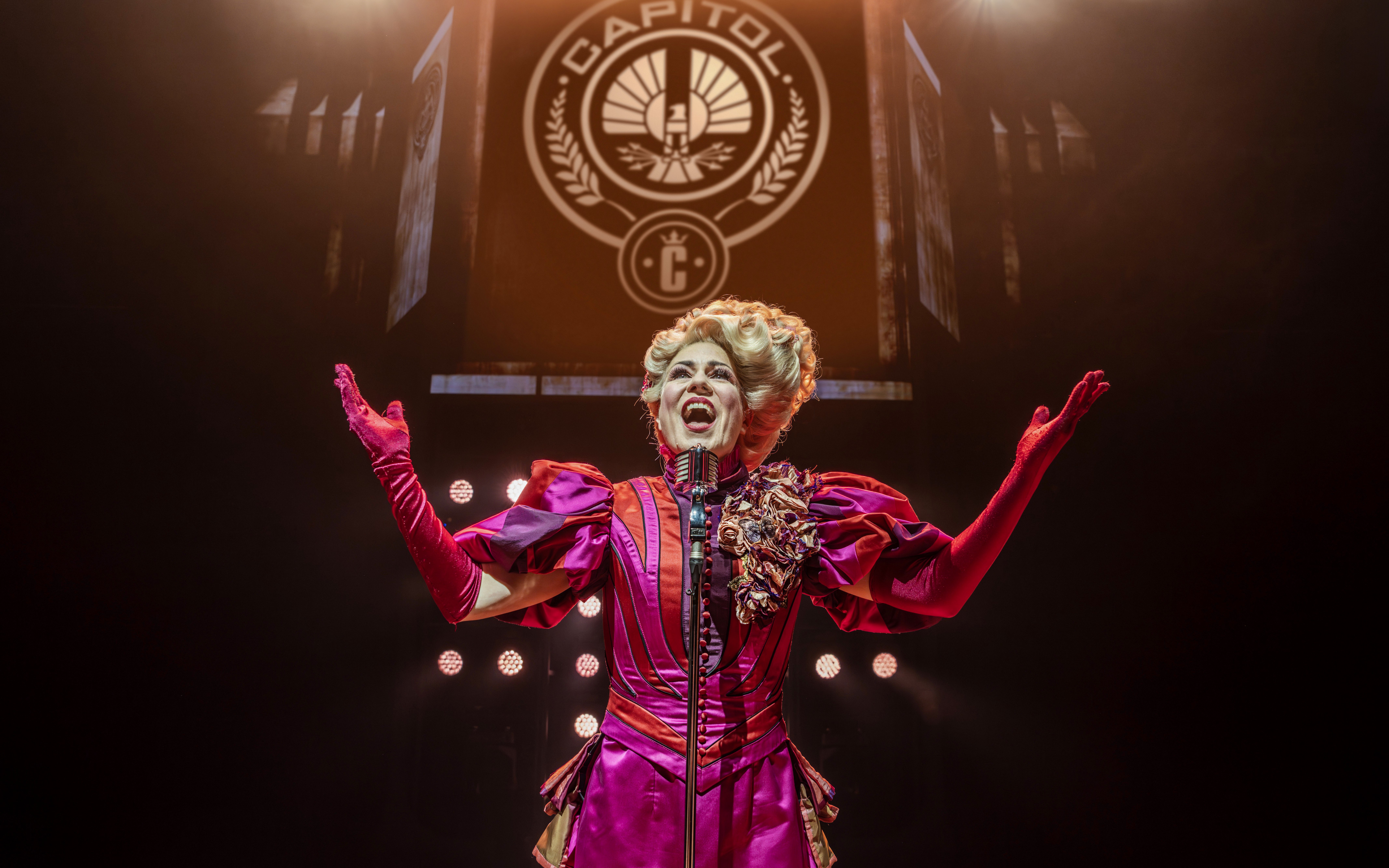 Performer in vibrant costume on stage during Hunger Games West End show.