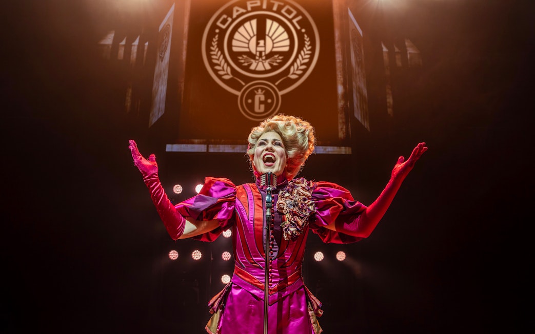 Performer in vibrant costume on stage during Hunger Games West End show.