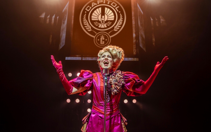 Performer in vibrant costume on stage during Hunger Games West End show.