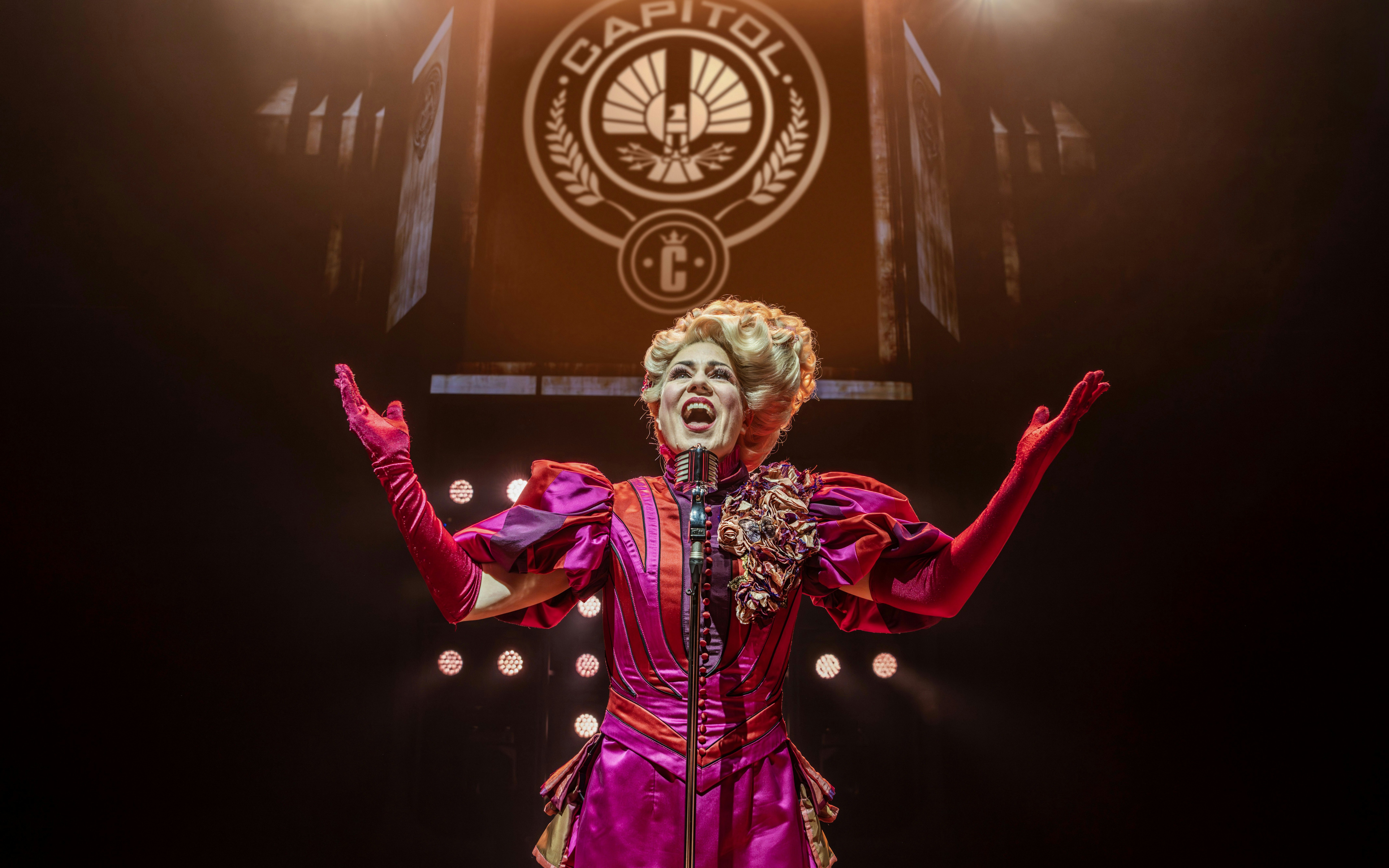Performer in vibrant costume on stage during Hunger Games West End show.