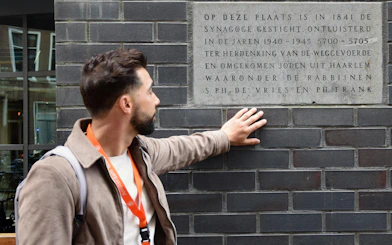 Tour guide pointing at WWII memorial plaque in Haarlem.