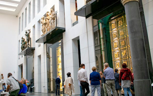 Visitors viewing sculptures and the Gates of Paradise at Florence Duomo Museum.