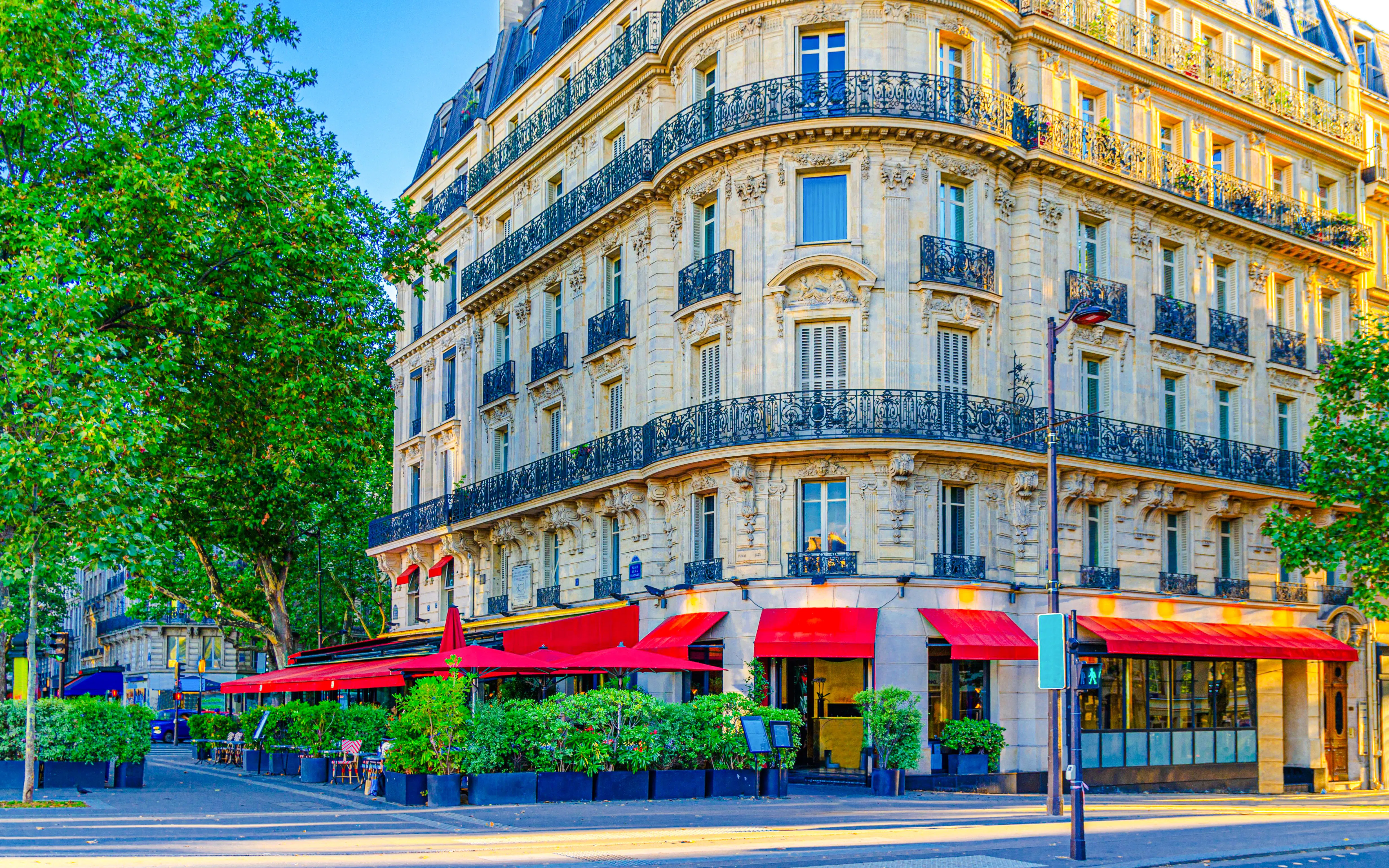 Parisian street cafe with red awnings on a corner building in Le Marais historic district.