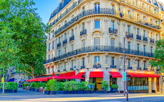 Parisian street cafe with red awnings on a corner building in Le Marais historic district.