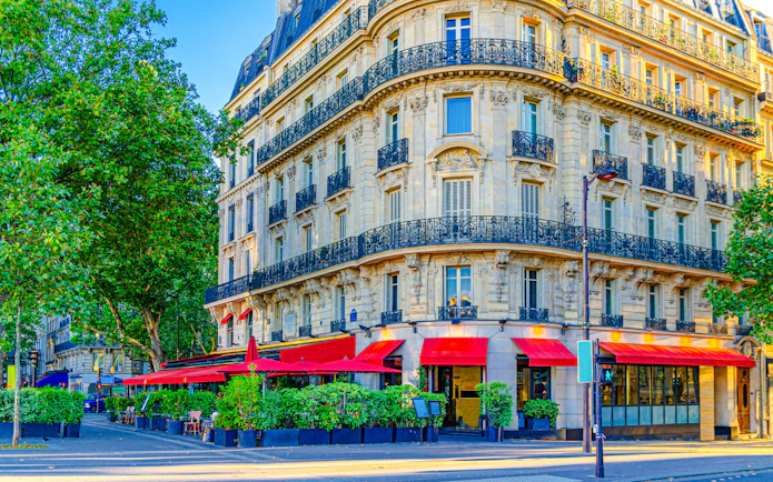 Parisian street cafe with red awnings on a corner building in Le Marais historic district.