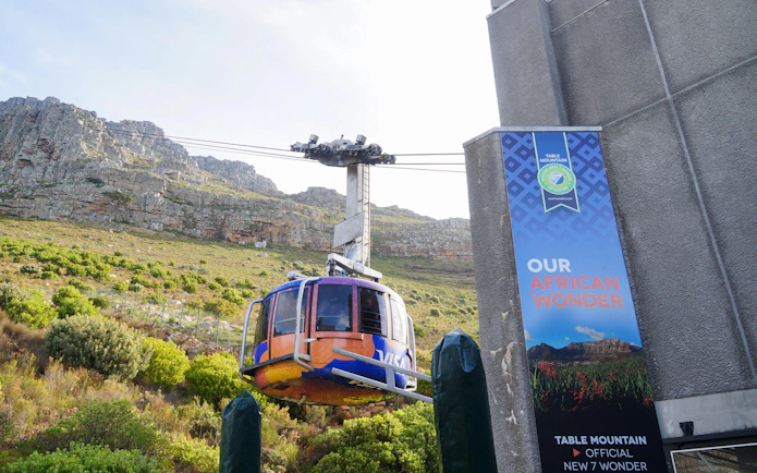 Cable car ascending Table Mountain, Cape Town, with rocky landscape in the background.