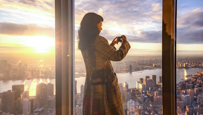 tourist enjoying views of new york skyline from Glass-enclosed observation deck on 102nd floor of empire state building