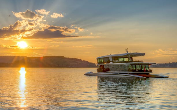 Catamaran cruising at sunset on a serene lake.