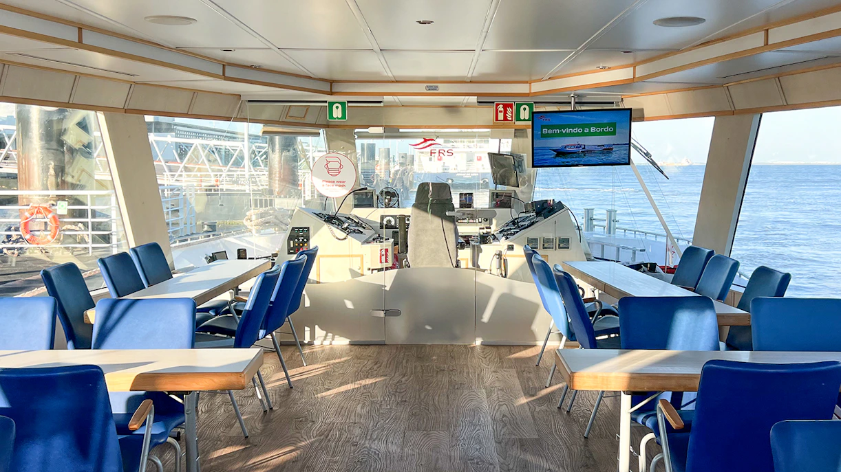 Interior of a boat cruise on the Tagus River with seating and navigation controls.