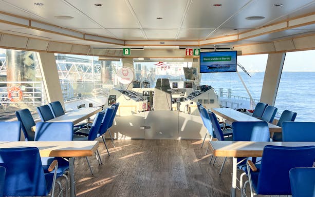 Interior of a boat cruise on the Tagus River with seating and navigation controls.