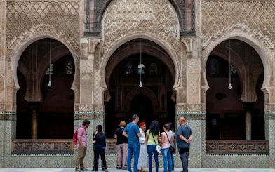 Visitors at Madrasa Bou Inania in Fes, Morocco, admiring intricate architecture.