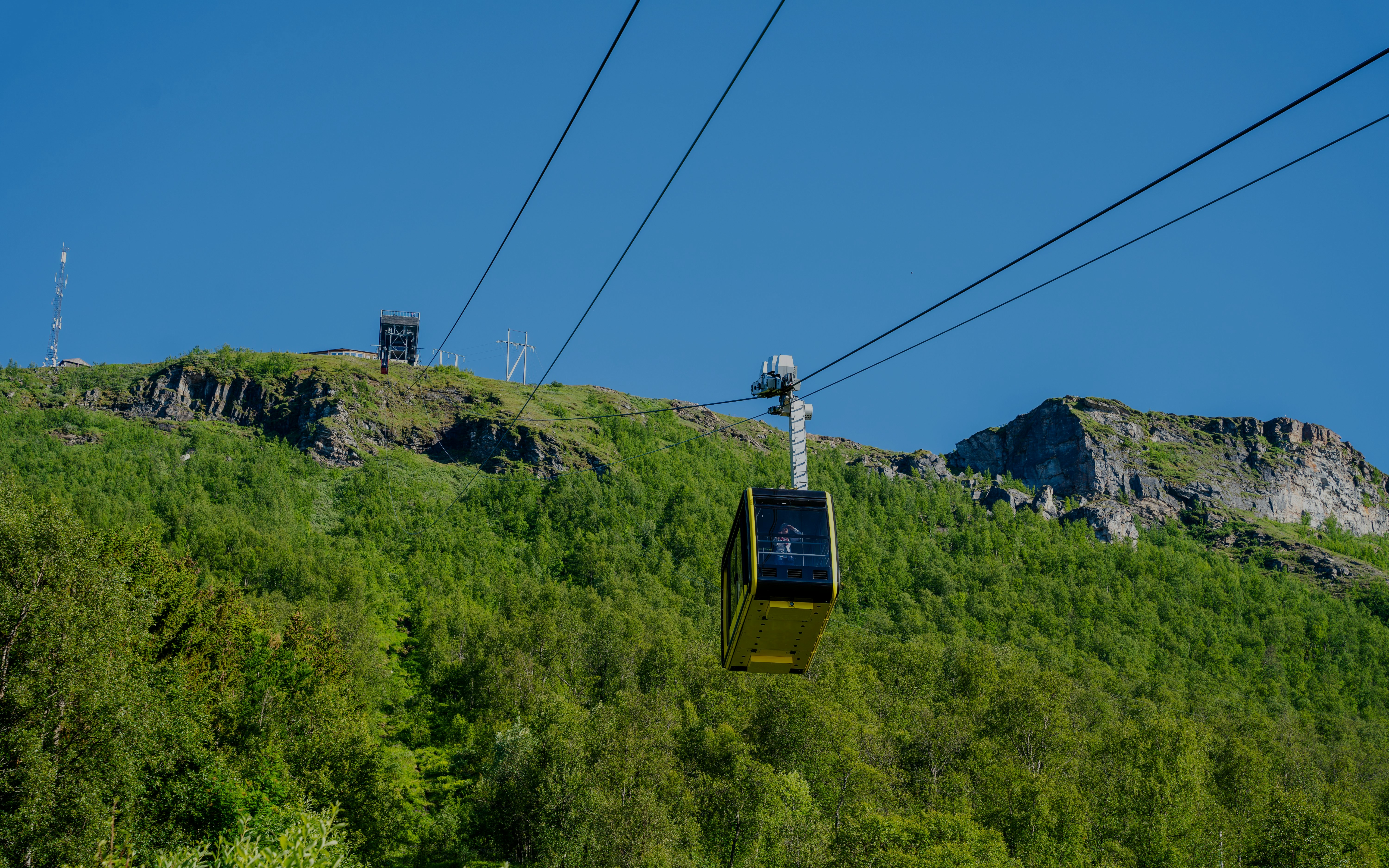 Fjellheisen Cable Car ascending over green hills in Tromsø, Norway.