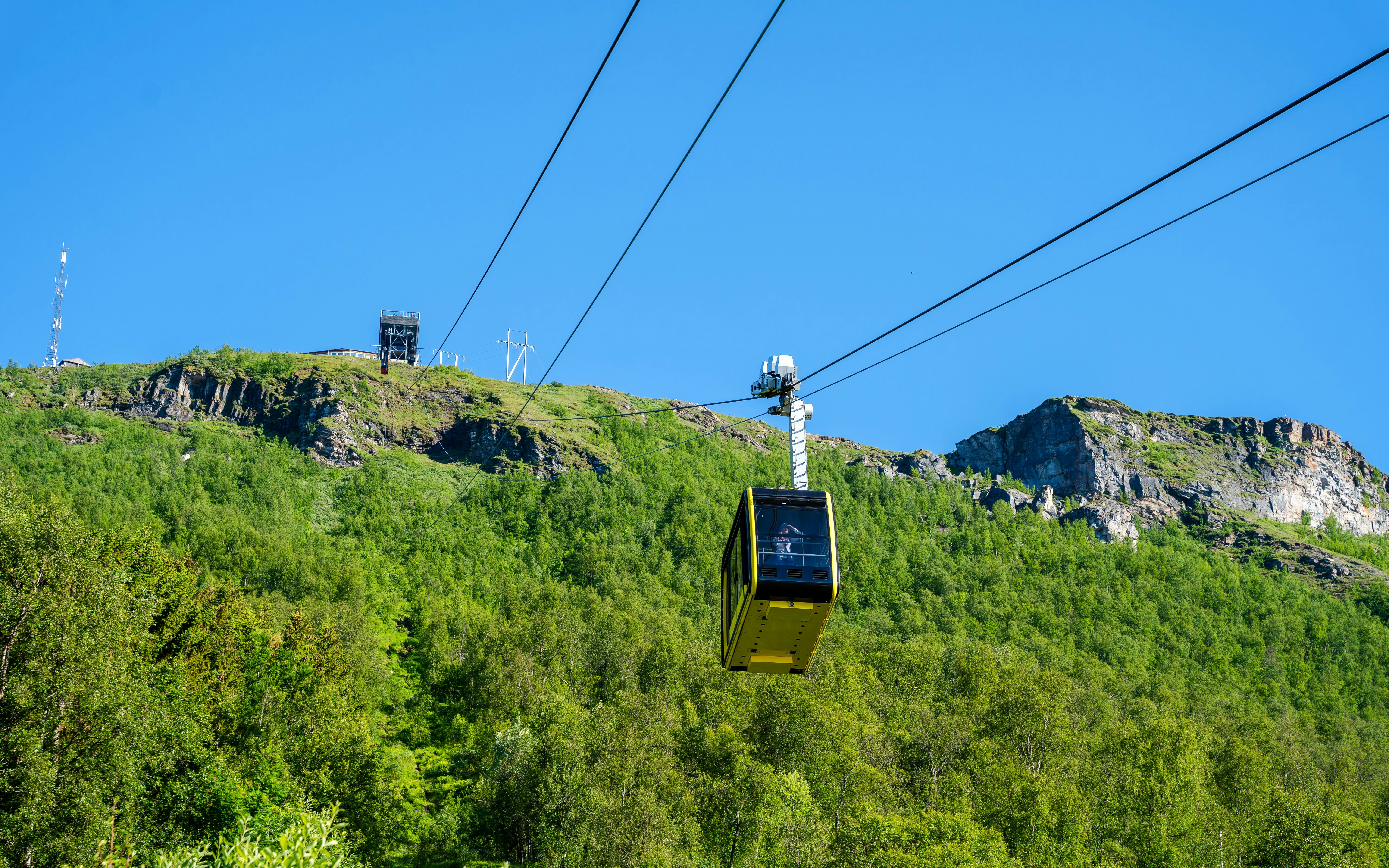 Fjellheisen Cable Car ascending over green hills in Tromsø, Norway.