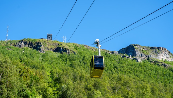 Fjellheisen Cable Car ascending over green hills in Tromsø, Norway.