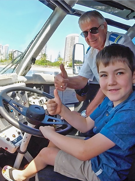Child and guide giving thumbs up inside Aquaduck vehicle, Sunshine Coast skyline visible.