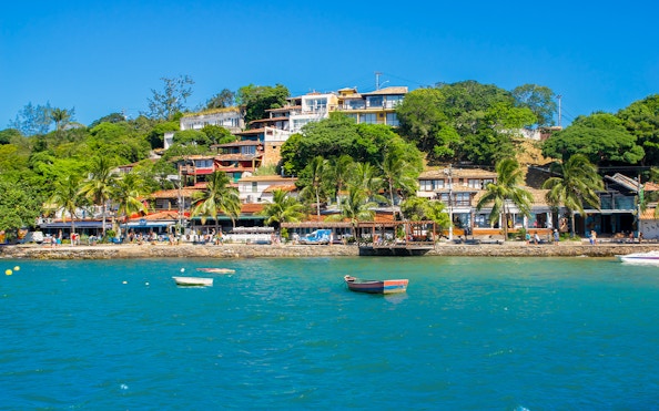 Boats on the water near Tucuns Beach, Buzios, with colorful hillside houses.