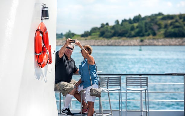 Couple taking a selfie on a Boston Premier Lunch Cruise with ocean view.