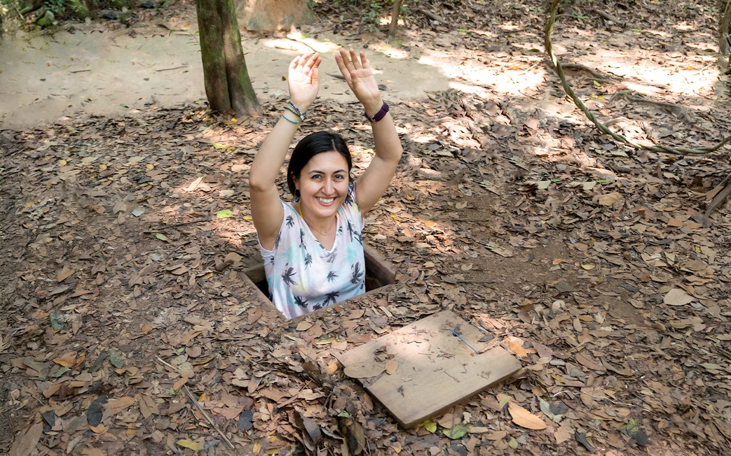 Woman emerging from a tunnel entrance at Cu Chi Tunnels, Vietnam.