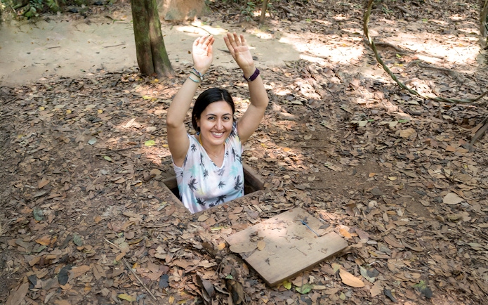 Woman emerging from a tunnel entrance at Cu Chi Tunnels, Vietnam.