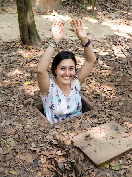 Woman emerging from a tunnel entrance at Cu Chi Tunnels, Vietnam.