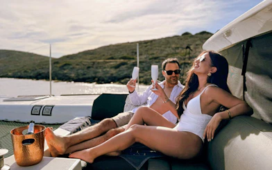 Couple relaxing with drinks on a catamaran during Heraklion cruise.
