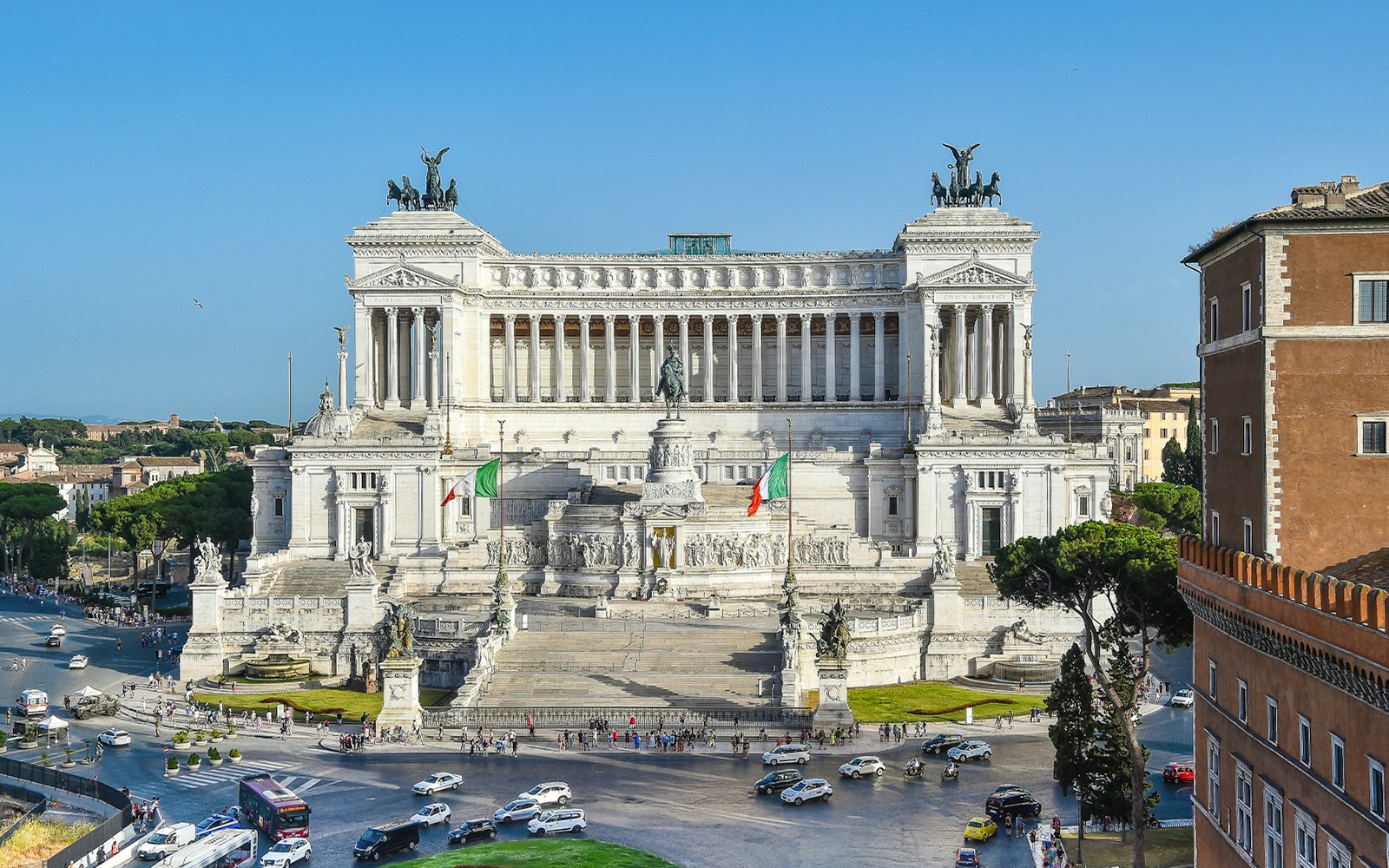 Altar of the Fatherland in Rome with Italian flags and surrounding cityscape.