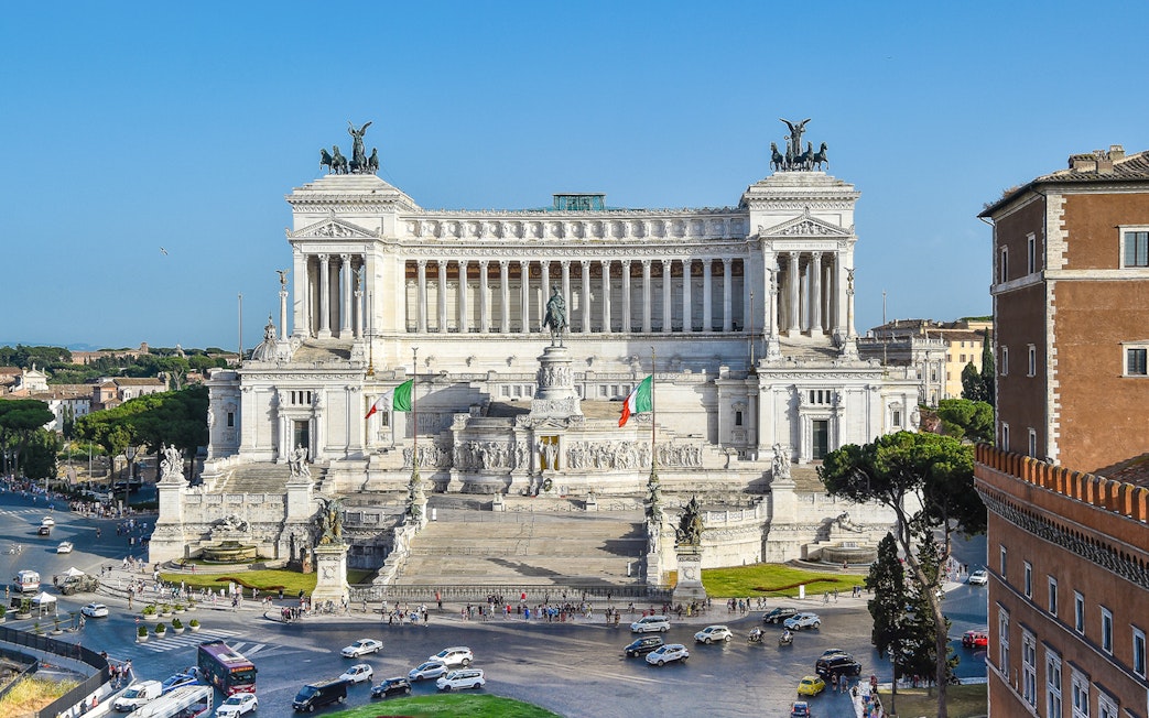 Altar of the Fatherland in Rome with Italian flags and surrounding cityscape.