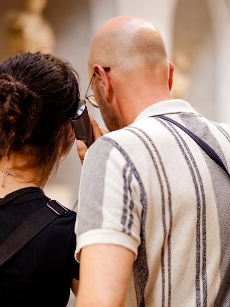 Guests using audio guide in museum hallway.