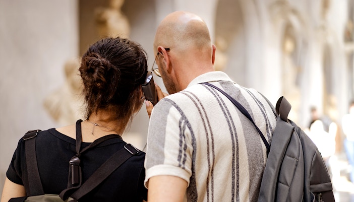 Guests using audio guide in museum hallway.