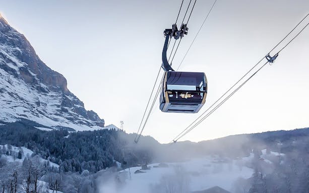 Eiger gondola ascending snowy mountain towards Jungfraujoch, Switzerland.