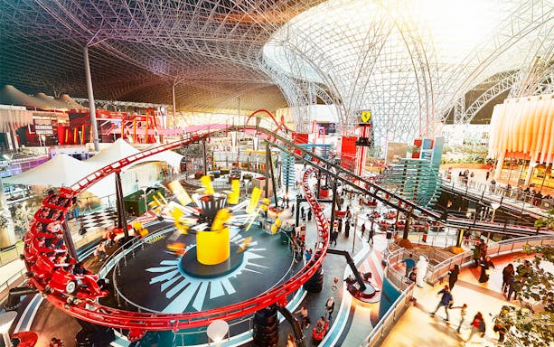 Ferrari World Abu Dhabi indoor roller coaster with visitors and iconic architecture.