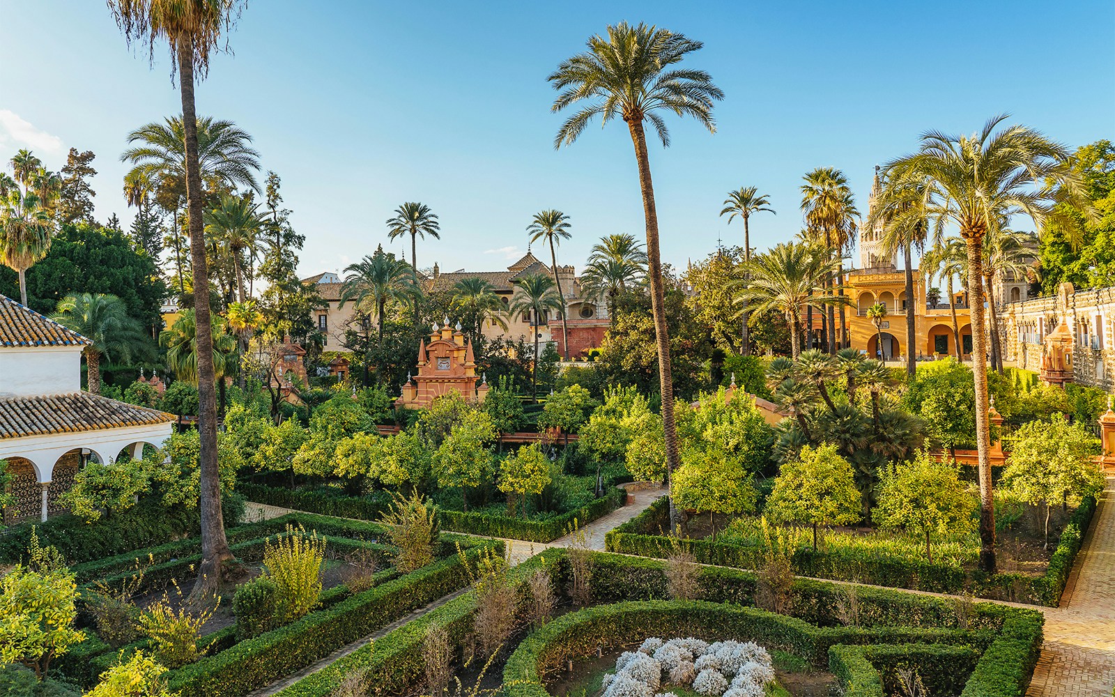Tourists exploring the stunning architecture of Alcazar of Seville, with a view of Seville Cathedral and Giralda in the background, available with skip-the-line tickets