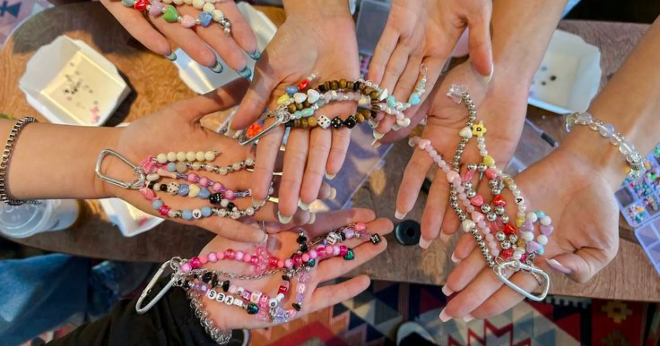 Hands displaying colorful handmade bracelets and necklaces at a workshop in Essaouira.