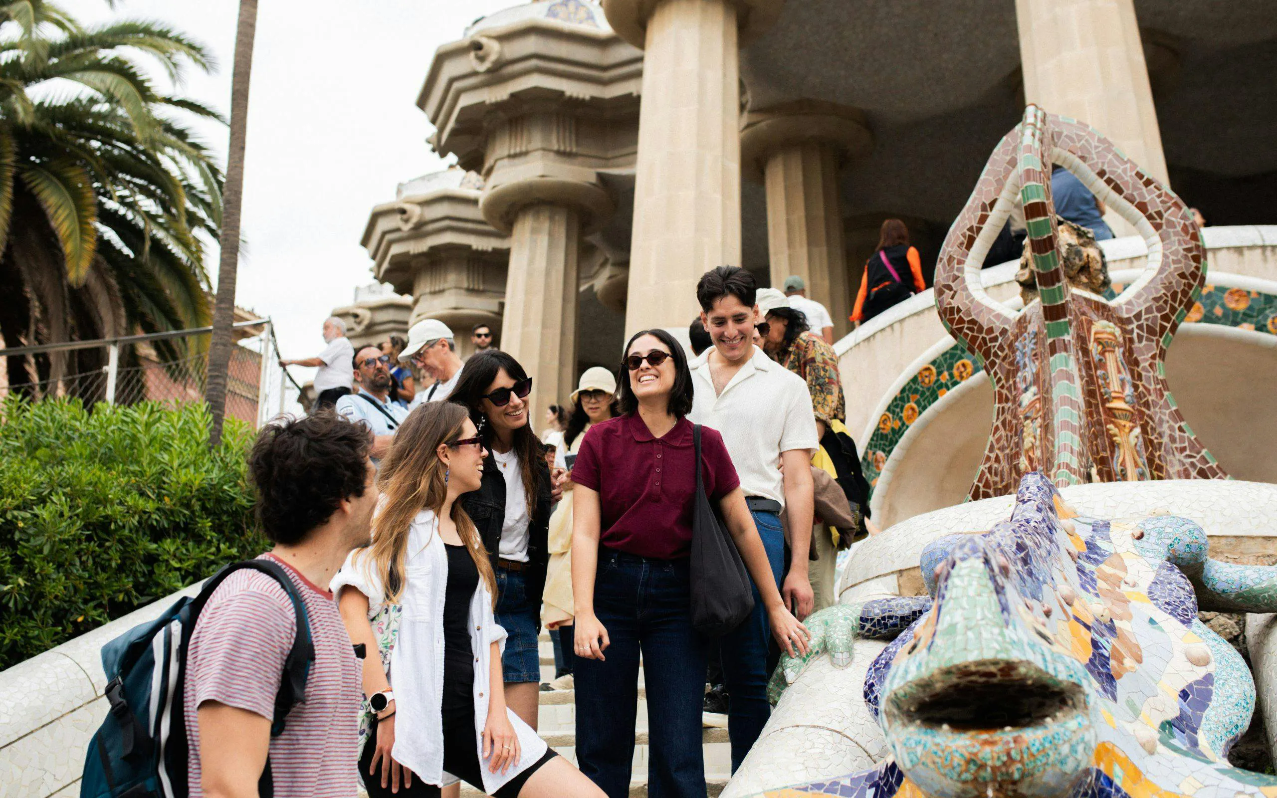 Tourists with guide at Park Güell near mosaic lizard sculpture, Barcelona.
