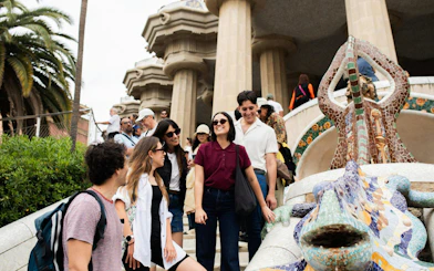 Tourists with guide at Park Güell near mosaic lizard sculpture, Barcelona.