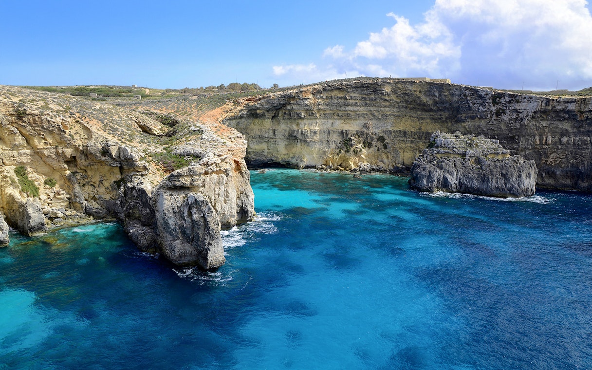 Rocky cliffs and clear blue waters at the Blue Lagoon, Malta.
