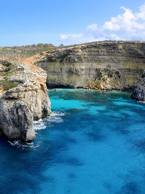 Rocky cliffs and clear blue waters at the Blue Lagoon, Malta.