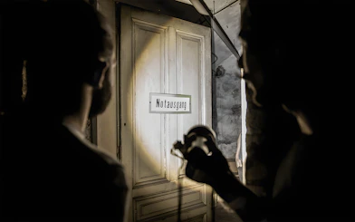 Dimly lit cellar with "Notausgang" sign during Historical Pharmacy Cellar Guided Tour.